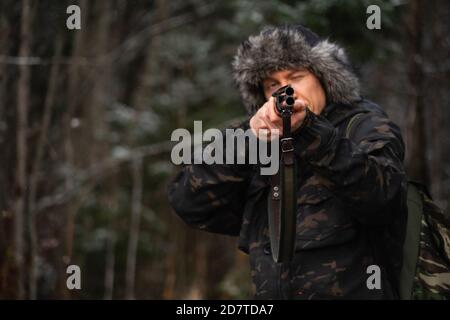 Chasseur visant un fusil de chasse dans une forêt d'hiver Banque D'Images