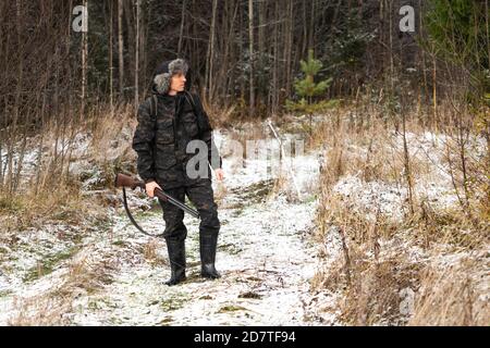 Hunter avec une arme à feu et un sac à dos en hiver forêt Banque D'Images