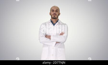 Médecin arabe sérieux homme mature avec bras croisés sur gradient Banque D'Images