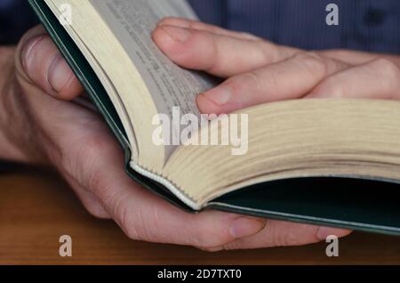 Le livre est entre les mains en gros plan. Livre épais en pastille dure dans les mains des hommes. Concept de lecture et d'auto-éducation Banque D'Images