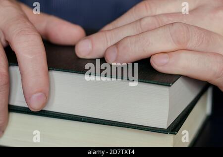 Pile de livres dans la couverture rigide et les mains des hommes. Les mains se trouvent au-dessus des livres épais fermés. Concept d'auto-éducation et d'auto-développement. Banque D'Images