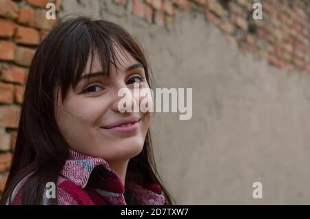 Portrait d'une jeune femme souriante et gaie aux cheveux sombres et amples. Belle femme en chemise à carreaux rouge regarde l'appareil photo. Banque D'Images