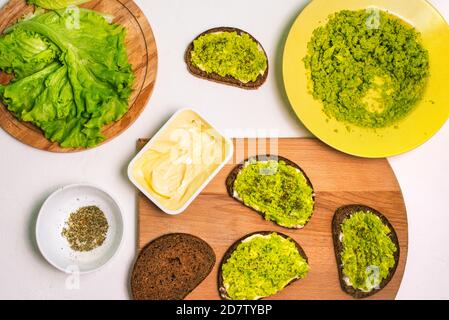 Sandwichs maison avec avocat. Purée d'avocat, pain, fromage à la crème sur une table blanche Banque D'Images