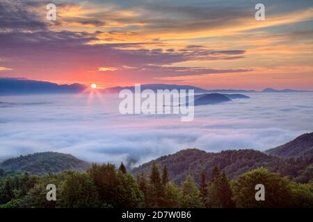Lever du soleil à l'aube au-dessus de la brume enveloppée bassin de Ljubljana, colline de Grmada, Tehovec, Slovénie Banque D'Images
