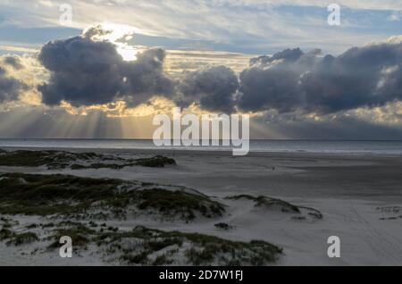 Île d'Amrum, Allemagne : rayons du soleil émergeant à travers les nuages sombres de la tempête sur la plage d'Amrum. Le coucher du soleil est masqué par un front de nuage épais annonçant mauvais Banque D'Images