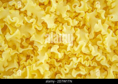 Fond de pâtes italiennes ondulées sèches. Une alimentation traditionnelle saine. Vue de dessus. Macro gros plan. Photo de haute qualité Banque D'Images