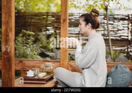 Vue latérale d'une belle femme qui boit du thé chinois à l'extérieur. Banque D'Images