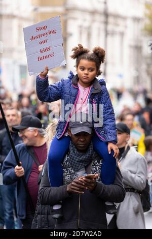 Un enfant avec un écriteau de protestation se promette en pigeback lors d'un rassemblement anti-verrouillage à Londres, le 24 octobre 2020 Banque D'Images