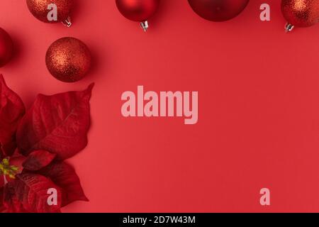 Joyeux Noël. plat avec poinsettia et boules de Noël sur fond rouge. Banque D'Images