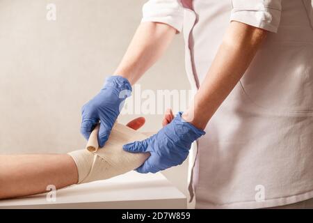 Le médecin impose un bandage élastique au poignet du patient. Réadaptation après la pluie Banque D'Images