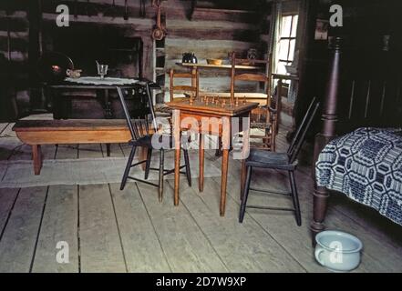 Des meubles simples sont vus dans l'intérieur de cette cabane en rondins de New Salem, maintenant un village historique qui était autrefois la maison d'Abraham Lincoln, 16e président des États-Unis. Il a déménagé dans la petite colonie du centre de l'Illinois en 1831 à l'âge de 22 ans et est resté six ans avant de devenir avocat et politicien. Notable est le plateau d'échecs avec des pièces de jeu en bois, et un pot de chambre en porcelaine à côté du lit. New Salem n'existait que pendant une douzaine d'années avant d'être abandonné. Reconstruit dans les années 1930 par le civil conservation corps (CCC), il compte 23 bâtiments en rondins. Banque D'Images