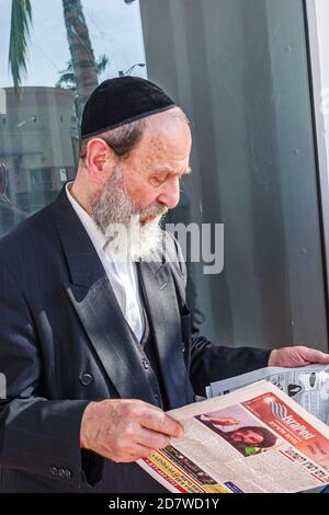 Miami Beach Floride, juif orthodoxe foi juive, lecture homme tabloïd senior barbe porte le port de yarmulka kippa, Banque D'Images