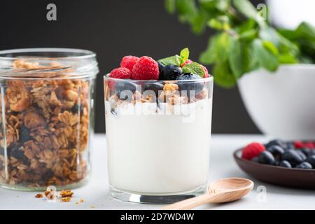 Yaourt à la granola et aux baies. Yaourt grec avec granola au miel d'avoine, framboises et bleuets dans un pot Banque D'Images