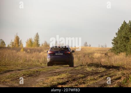 VOLKOVO, RUSSIE - 4 OCTOBRE 2020 : le Nissan bleu Qashqai se déplace sur la route de la terre en automne champ à la lumière du jour. Banque D'Images