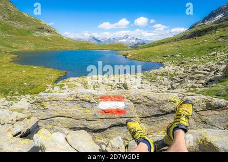 Chaussures de randonnée de randonneur reposant sur des rochers aux lacs de Baldiscio, Val Febbraro, Valchiavenna, Vallespluga, Lombardie, Italie Banque D'Images