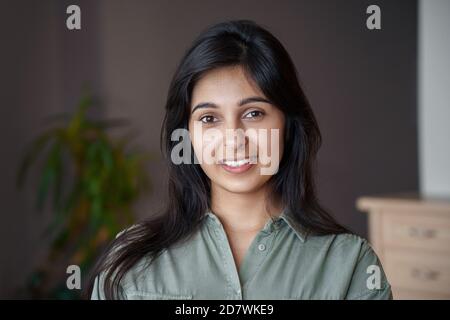 Jeune femme indienne souriante regardant l'appareil photo à la maison, portrait de tête. Banque D'Images