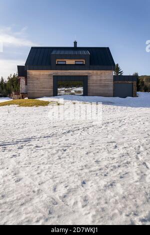 Maison en bois avec grande fenêtre miroir réfléchissante, mur design, architecture moderne, jour d'hiver ensoleillé Banque D'Images