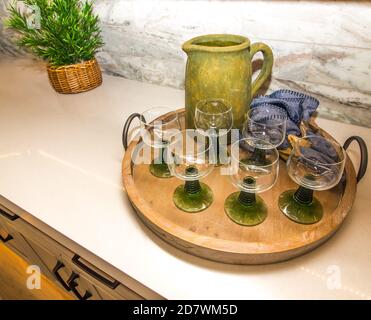 Plateau de service en bois avec verres de couleur et pichet verseur Banque D'Images