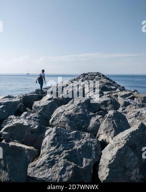 Femme marchant sur des rochers, allant vers l'eau Banque D'Images