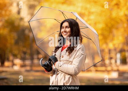 Concept de la saison d'automne. Jeune femme à la mode avec une tenue élégante tenant un parapluie et souriant au parc jaune Banque D'Images