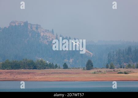 Lost Creek Lake Near Prospect, Oregon / États-Unis - 7 septembre 2014 : un petit avion de lutte contre l'incendie se prépare à ramasser de l'eau comme il vient dans le bas au-dessus du sho Banque D'Images