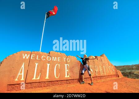 Happy Warinfree touriste woman at Alice Springs Welcome Sign in Central Australia. Tourisme dans le désert de l'Outback Red Centre. Voyage découverte sur route dans Banque D'Images