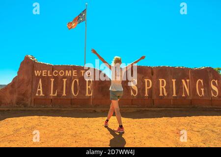 Happy Warinfree touriste woman at Alice Springs Welcome Sign in Central Australia, Northern Territory. Tourisme dans le désert de l'Outback Red Centre. Déplacement Banque D'Images