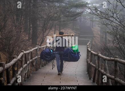 L'homme ouvrier carring des aliments ou routard pour le tourisme qui randonnée jusqu'au sommet et ses frais supplémentaires pour le travailleur à Huangshan montain, province d'Anhui, Banque D'Images