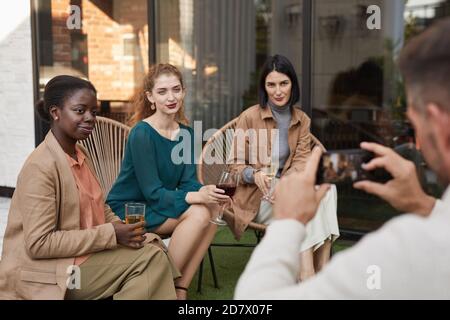 Portrait de trois femmes élégantes posant pour la photo et souriant à l'appareil photo tout en appréciant la fête en plein air sur la terrasse, espace de copie Banque D'Images