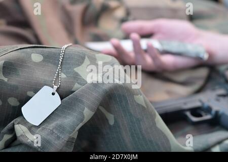 Un jeton militaire vide de soldat militaire mort se trouve sur des vêtements de camouflage. Suicide pendant le service militaire dans le concept de l'armée russe Banque D'Images