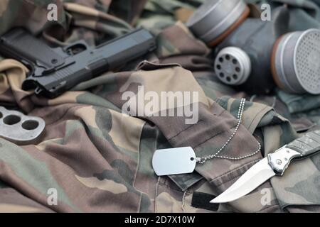 Les soldats stacker masque à gaz soviétique se trouve avec un pistolet et un couteau sur des vestes de camouflage kaki vertes. Étiquettes pour chien et porte-fusée en laiton. Post apocalypse survivre Banque D'Images