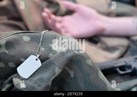 Un jeton militaire vide de soldat militaire mort se trouve sur des vêtements de camouflage. Suicide pendant le service militaire dans le concept de l'armée russe Banque D'Images