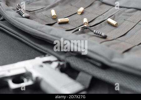 balles de 9 mm et pistolet se trouvent sur un sac à dos tactique noir. Ensemble d'éléments de service spéciaux ou d'un agent secret. Coquilles d'or dispersées autour du canon à main Banque D'Images