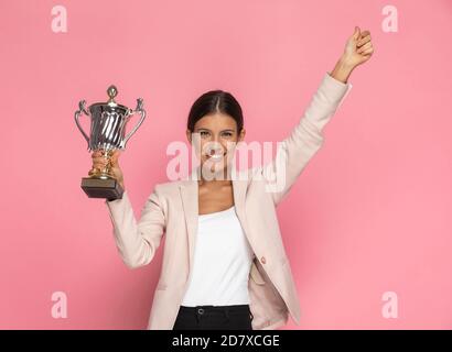 femme d'affaires mignonne tenant une tasse et donnant un pouce vers le haut dans l'air sur fond rose Banque D'Images