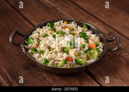 Riz végétal au brocoli, carottes et pois verts, dans une poêle sur fond de bois rustique foncé Banque D'Images