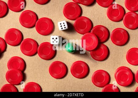 Le concept de jeux de société, un platlay d'un pion avec des pièces de jeu rouges et des dés, tiré d'en haut sur un fond marron Banque D'Images