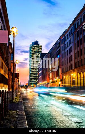 Paysage urbain de longue exposition dans le quartier central de Berlin, Allemagne, au coucher du soleil avant le crépuscule. Des voitures floues passent et quittent les sentiers de lumière. Banque D'Images