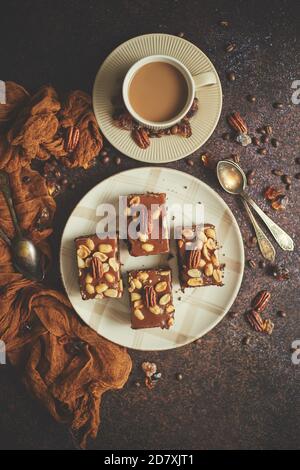 Gâteau au chocolat avec glaçage au caramel, pacanes et café chaud, sur fond rustique. Fraîchement cuit Banque D'Images