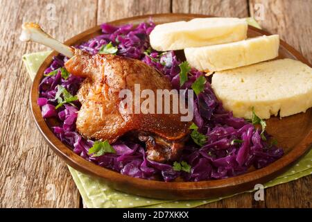 Cuisse de canard rôtie avec chou rouge et boulettes en gros plan dans une assiette sur la table. Horizontale Banque D'Images