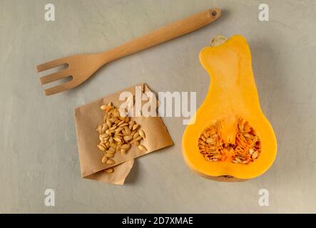 Composition de citrouille mi-mûre avec des graines sur parchemin et une fourchette en bois. Concept d'alimentation saine. Orientation horizontale, mise au point sélective, vue de dessus, f Banque D'Images