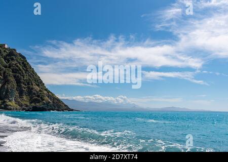Plage noire de Nonza en Corse sous un grand ciel bleu, mer bleue, vagues. Banque D'Images