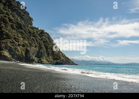 Plage noire de Nonza en Corse sous un grand ciel bleu, mer bleue, vagues. Banque D'Images