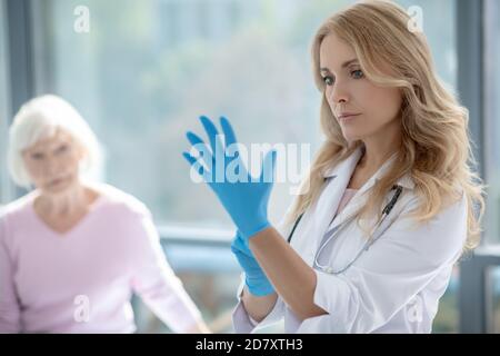 Jeune femme aux cheveux longs, jolie infirmière portant des gants de protection Banque D'Images