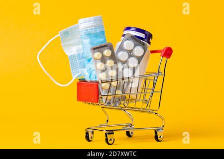 Un panier rempli de médicaments et d'un masque médical. Arrière-plan jaune. Gros plan. Le concept d'achat de médicaments. Banque D'Images