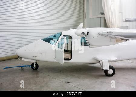 Avion léger bimoteur à ailes hautes avec porte ouverte dans le hangar Banque D'Images