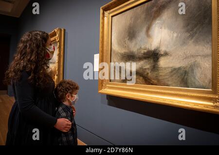 Londres, Angleterre. 26 octobre 2020. Une mère et un fils regardant l’huile de la tempête de neige de Turner sur toile pendant la vue de presse d’une grande exposition, Turner’s Modern World, Ouverture à la Tate Britain le 28 octobre 2020 dédiée à JMW Turner (1775-1851). Turner’s Modern World révèle comment le peintre paysagiste britannique a trouvé de nouveaux moyens de capturer les événements quotidiens, de l’impact de la technologie sur le monde naturel aux effets de la modernisation sur la société. (Photo de Sam Mellish / Alamy Live News) Banque D'Images