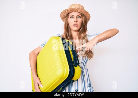 Jeune femme caucasienne aux cheveux blonds portant la robe d'été et tenant le sac de cabine détendu avec une expression sérieuse sur le visage. Simple et naturel a Banque D'Images