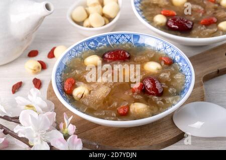 Gros plan de la soupe traditionnelle chinoise douce aux champignons blancs avec graines de lotus, dattes rouges (jujujube) et baies de carcajou (baie de goji, baie de gogyberry) sur le dos blanc Banque D'Images