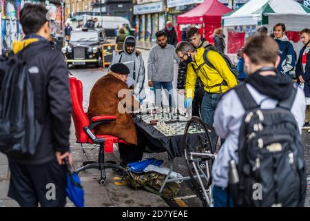 Street Chess Brick Lane Londres - un joueur d'échecs joue Matchs d'échecs rapides avec les touristes et les passants dans le populaire Londres Marché du dimanche de Brick Lane Banque D'Images