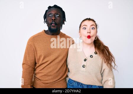 Couple interracial portant des vêtements décontractés faisant le visage de poisson avec des lèvres, fou et comique geste. Expression drôle. Banque D'Images